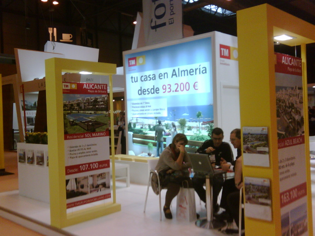 Ein Raum mit Menschen, die an einem Tisch arbeiten, umgeben von verschiedenen Flyern.