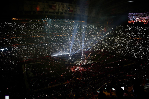 Gro├čer Menschenauflauf in einem hell erleuchteten Stadion bei Nacht, mit einem Bildschirm auf der rechten Seite, der die Ergebnisse der Super Bowl XLVII-Halbzeitpause anzeigt.