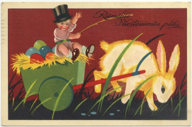 Eine alte Postkarte mit einem Baby in einem Zylinder, das einen Karren voller bunter Ostereier schiebt, begleitet von einem Hasen, mit handgeschriebenen Ostergrü├čen.