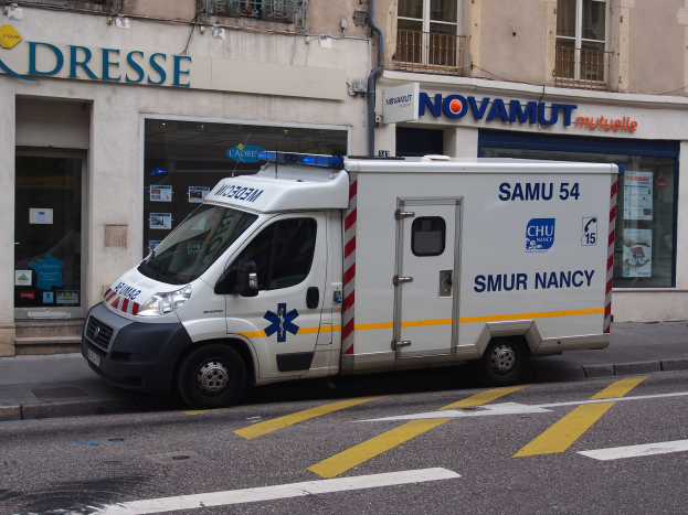 Ambulanz auf dem Seitenstreifen vor einem Gebäude mit einem Krankenhausschild geparkt.