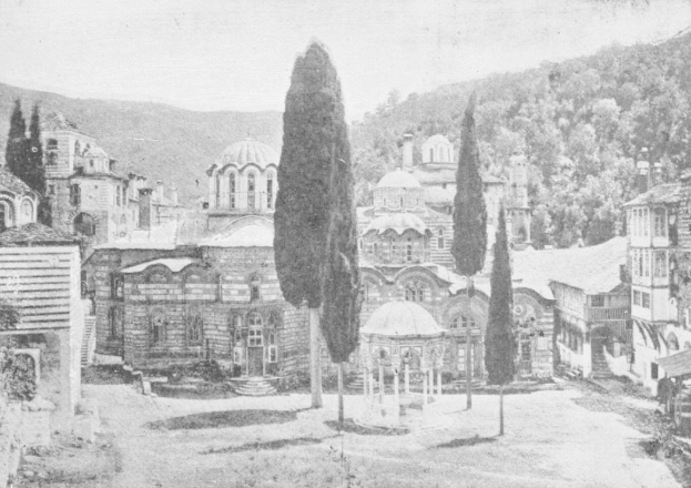 Ein Schwarz-Weiß-Foto einer Stadtstraße mit Gebäuden, Bäumen, Pfählen und einem Hügel im Hintergrund, mit dem Text "Das Heilig-Kreuz-Kirchen" unten.