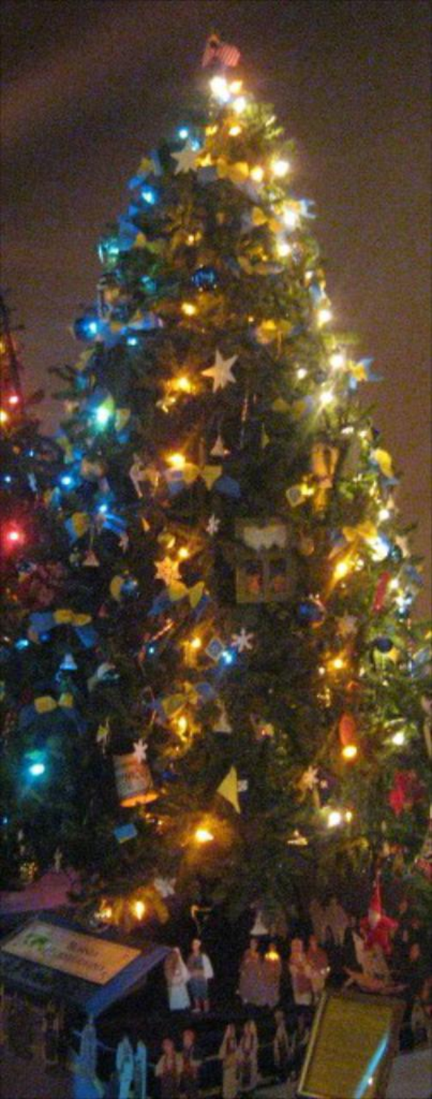 Ein geschmückter Weihnachtsbaum mit Statuen von Menschen auf einem Tisch darunter.