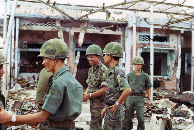 Ein demoliertes Haus mit ein paar Soldaten in der N├Ąhe.