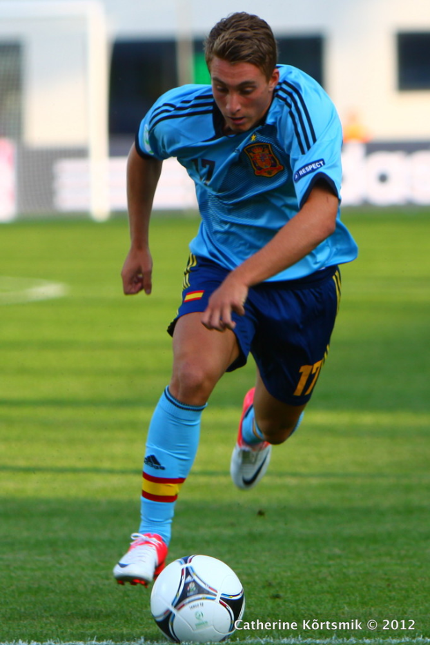 Ein Mann in einem blauen T-Shirt spielt FÃ¼ßball auf einem Feld.