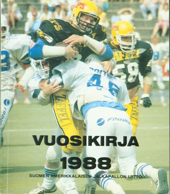 Gruppe von Menschen in Sportkleidung und Helmen, die Fußball auf einem Feld spielen, mit Zuschauern, die auf einer Treppe im Hintergrund sitzen; Text unten lautet "Vuosikirja 1988 - Suomen Amerikkaisen Jalkapallon Litto".