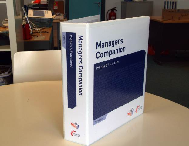 Ein Buch auf einem Tisch mit einem Stuhl dahinter, in der Nähe einer Tür, Feuerlöscher, Akten und andere Gegenstände.
