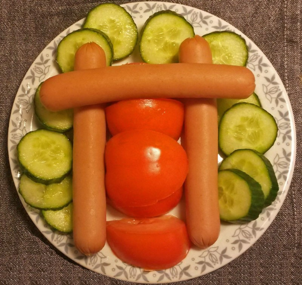 Ein Teller mit Tomaten- und Gurkenscheiben, die wie eine Wurst angeordnet sind.