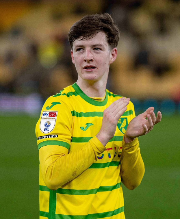 Ein junger Mann in einem gelb-grünen T-Shirt klatscht auf einem Fußballfeld begeistert in die Hände, der Hintergrund ist unscharf.