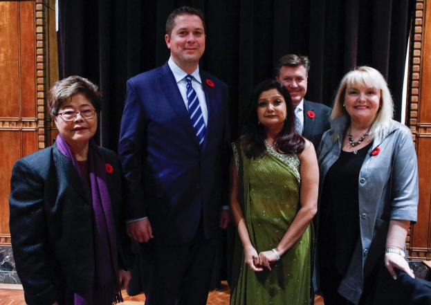 Eine Gruppe von Menschen vor einem schwarzen Vorhang mit einer hölzernen Wand im Hintergrund, die scheinbar Mitglieder der Freien Demokraten bei einer Versammlung sind.