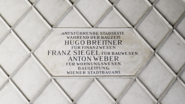 Ein Steinplakette an einer Wand mit den Namen "Hugo Breitner, Franz Siegel, Anton Weber" darauf.