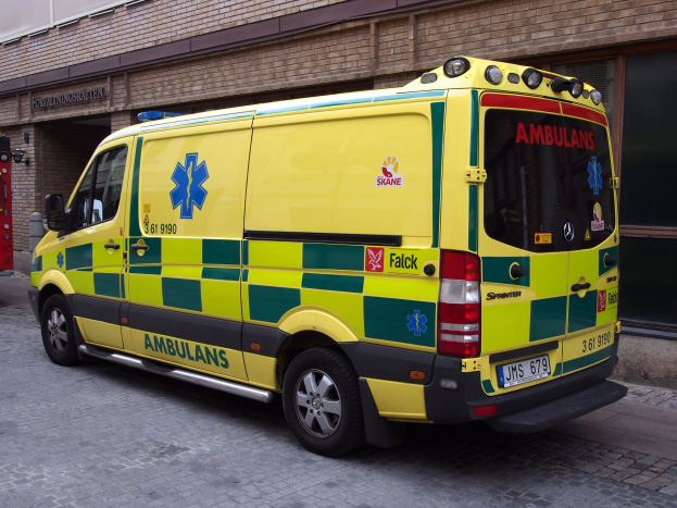 Ein Rettungswagen steht vor einem Backsteingebäude auf der Straße, auf dem Text steht, und ein Feuerlöscher ist auf der linken Seite des Bildes zu sehen.