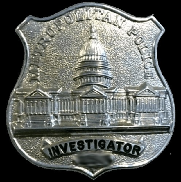 Silbernes Polizei-Detektivabzeichen mit 'Detektiv' Text auf weißem Hintergrund.