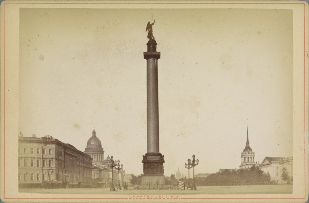 Altes Schwarz-Weiß-Foto eines Denkmals in einem städtischen Platz, eingerahmt von Gebäuden, Straßenlaternen, Bäumen und einem klaren Himmel, mit Text am unteren Rand.