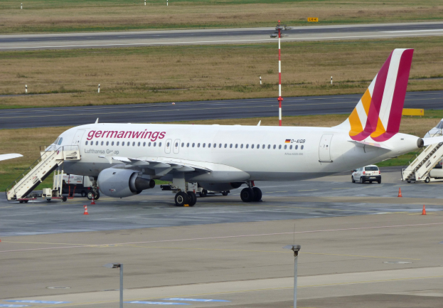 Germanwings Airbus A320-200 am Frankfurt Airport geparkt mit Bodenfahrzeugen, Verkehrskegeln, Versorgungsmästen und grüner Fläche im Hintergrund.