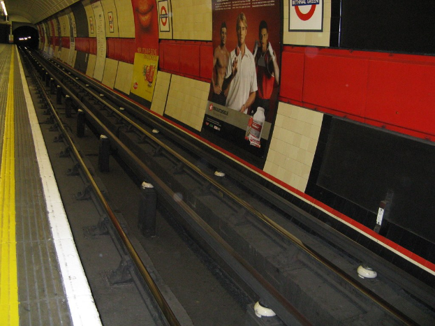 Eine Bahnstrecke mit Plakaten an der Wand.