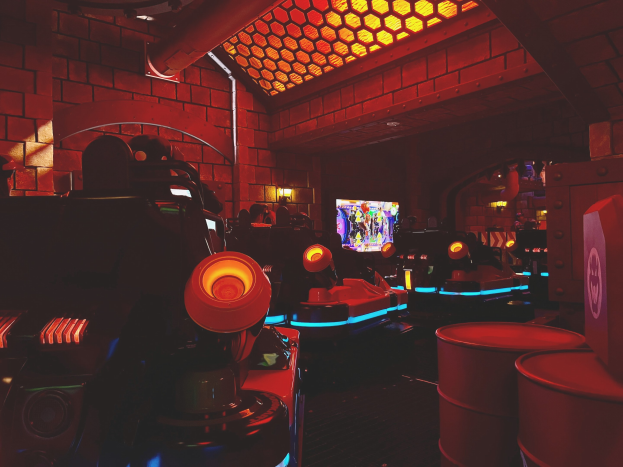 Ein hell erleuchteter Raum voller verschiedener Arcade-Videospielautomaten, Bildschirme und farbige Lichter, mit einer Decke mit Oberlichtern.