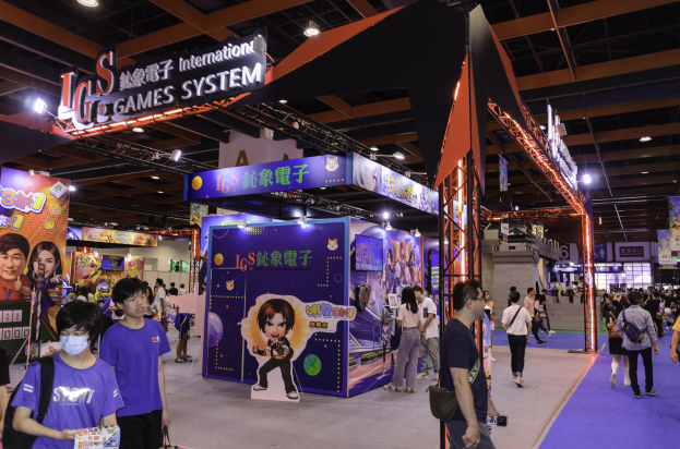 Eine Gruppe von Menschen geht durch einen Veranstaltungsraum auf einer Gaming-Messe in China, einige tragen Taschen und halten Gegenstände, mit Displaytafeln, Deckenleuchten und Teppichboden.