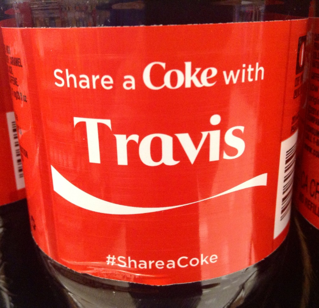 Eine durchsichtige Glasflasche mit der Aufschrift "Share a coke with TRAVIS".