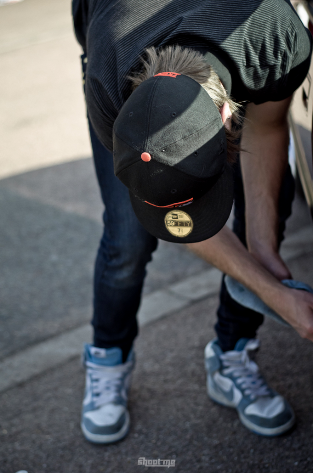 Eine Person mit einer schwarzen Mütze, schwarzem T-Shirt, Jeans und Schuhen, die auf einem Weg steht.