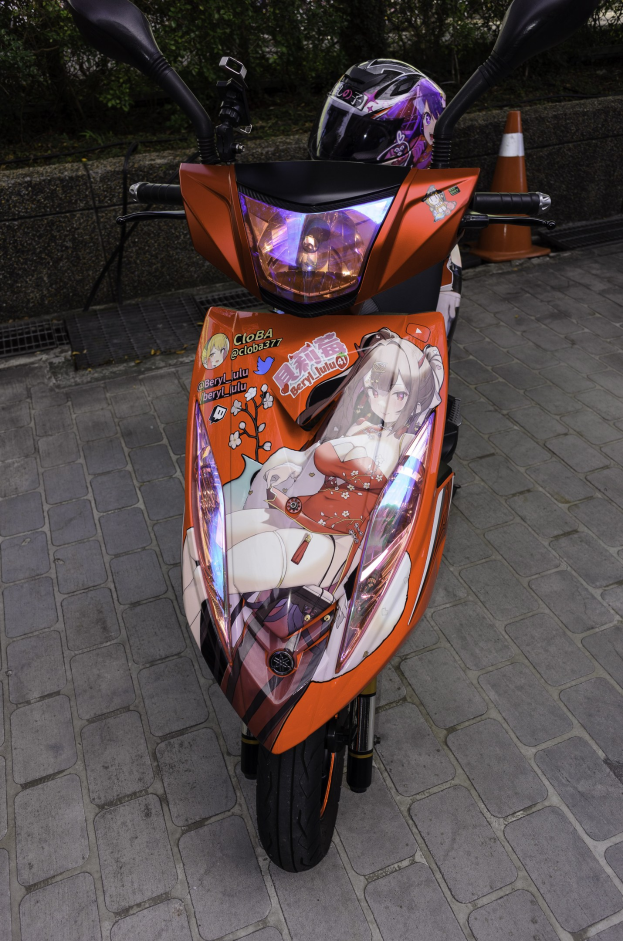 Orangescooter auf der Straßenseite mit einem Helm darauf, einer Verkehrskegel, einer Wand und Bäumen im Hintergrund.