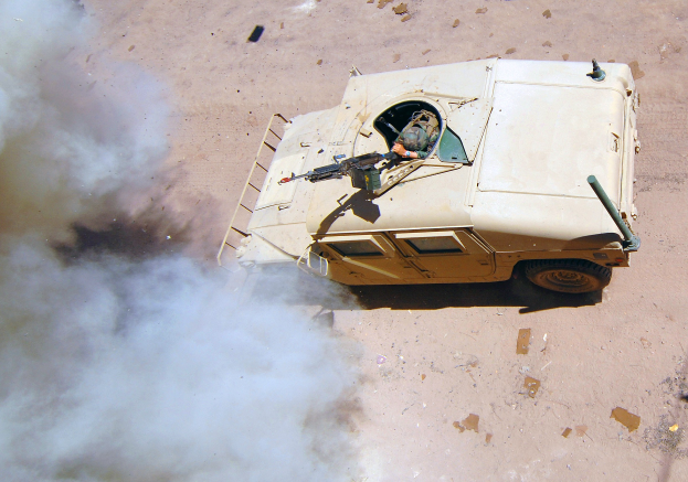 Panzerfahrzeug fährt auf einem Schotterweg mit Rauch aus dem Fahrzeug und einer Person im Inneren.
