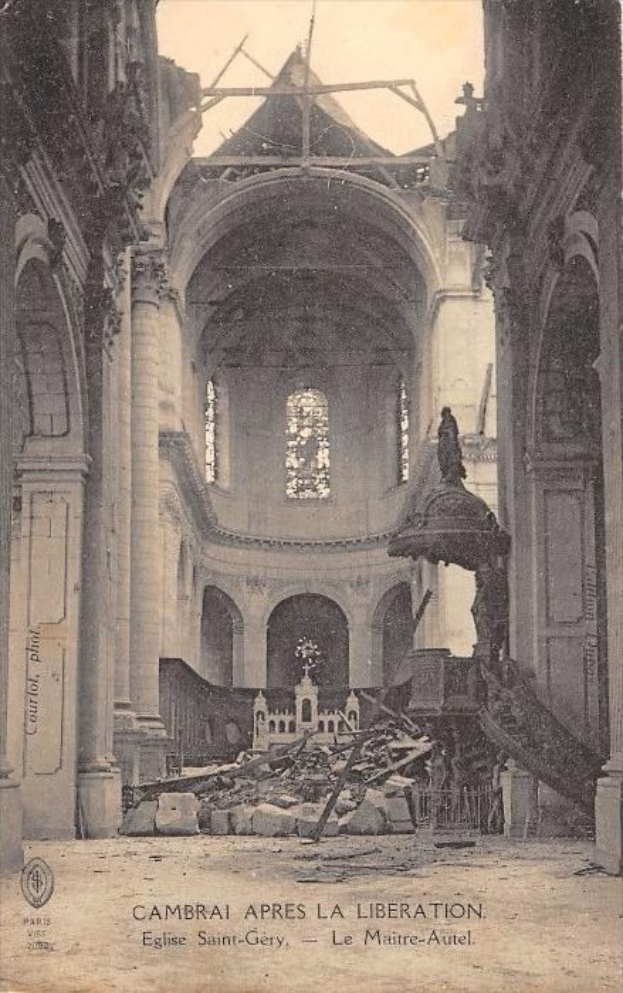 Ein Schwarz-Weiß-Foto des zerstörten Innenraums einer Kirche, das verkohlte Säulen, Bögen und Fenster zeigt, mit einem Text am unteren Rand, der 'Cambrai Apres La Liberation' lautet.