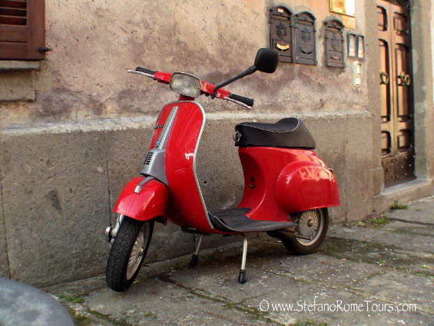 Ein rotes Moped steht vor einem Haus mit einer T├╝r und Fenstern auf einer Stra├če mit etwas sichtbarem Text.