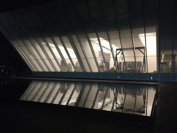 Ein Museum mit Glaswänden und Dach, das von Stadtlichtern beleuchtet wird und eine friedliche Atmosphäre widerspiegelt.