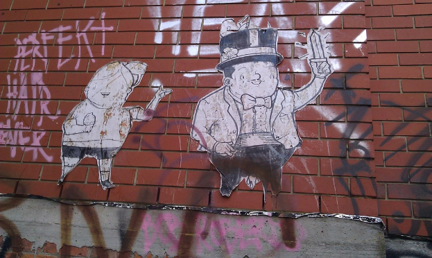 Eine Backsteinwand mit verschiedenen Postern und Graffiti.
