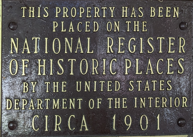 Eine Metalltafel an einem Gebäude lautet "Dieses Gebäude steht unter Denkmalschutz".