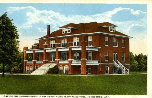 Eine Postkarte, die das Wohnheim der Staatlichen Landwirtschaftsschule in Jonesboro, Arkansas zeigt, mit einem großen Gebäude mit Fenstern, Treppen mit Geländern und umgebenden Bäumen unter einem bewölkten Himmel, mit Text unten.