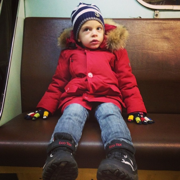 Ein Mädchen in einer roten Jacke auf einem Sofa sitzend.