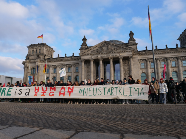 Gruppe von Menschen vor dem Reichstag in Berlin mit einem Banner "Wir sind ein Menschenrecht"
