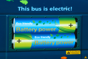 Blauer Elektrobus mit "Dieser Bus ist elektrisch"-Schriftzug und zwei sichtbaren Seitenbatterien.