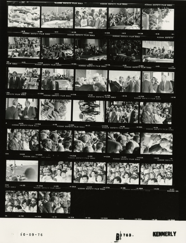 Schwarzes und weißes Foto einer vielfältigen Menschenmenge, die fröhlich in Richtung eines Fernsehbildschirms schaut, mit Text am unteren Rand.