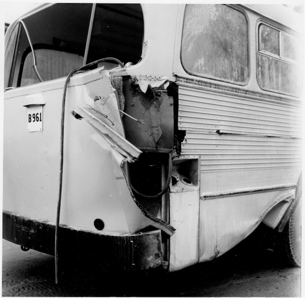 Schwarzes und weißes Foto eines Busses mit schwerer Frontschaden nach einem Autounfall auf der Straße.
