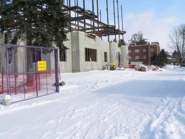 Eine schneebedeckte Landschaft mit Gebäuden, Bäumen und Zäunen im Hintergrund unter einem klaren Himmel.
