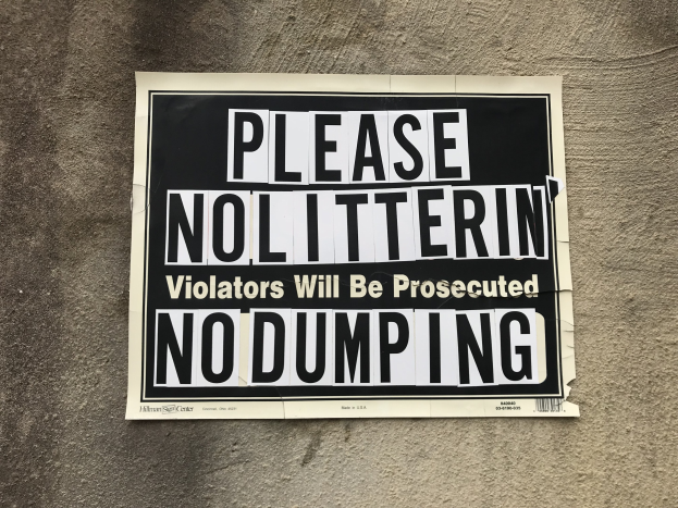Schwarzes und weißes Schild an einem Gebäude mit der Aufschrift "Bitte Kein Müll Verunreiniger Werden Verfolgt Keine Ablagerung."