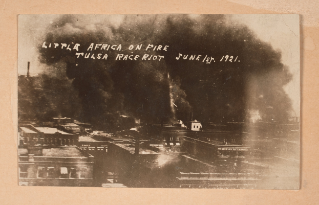 Schwarz-weiß-Foto einer Stadt mit Rauch, der aus der Mitte aufsteigt, wo Text zu sehen ist, und Gebäuden unten, die eine belebte Stadtlandschaft andeuten.