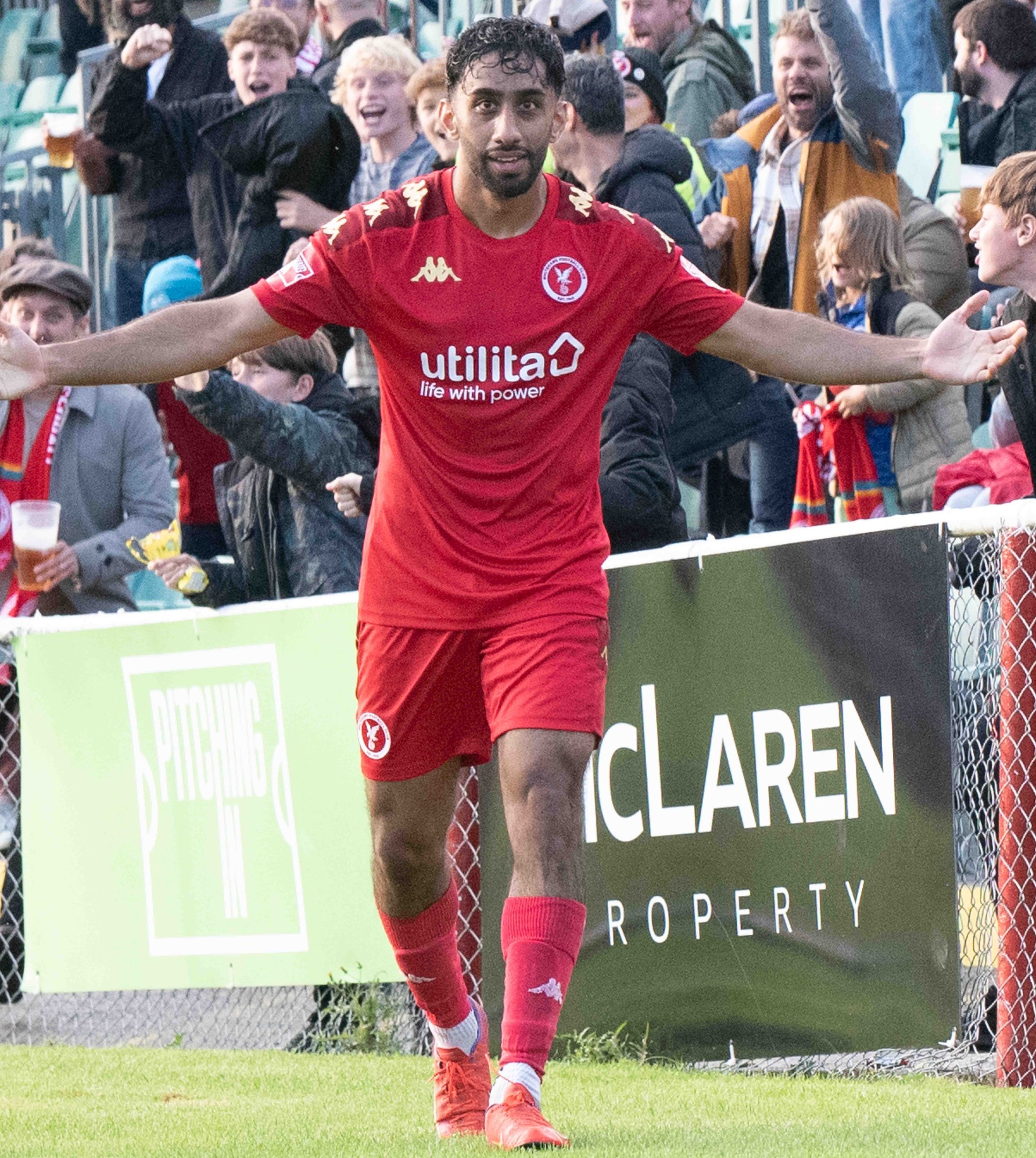 Ein Fußballspieler in roter Uniform rennt mit ausgestreckten Armen auf einem Feld, umgeben von einer Menge, mit einem "Middlesbrough FC v Swansea City - Sky Bet Championship"-Schild im Hintergrund.